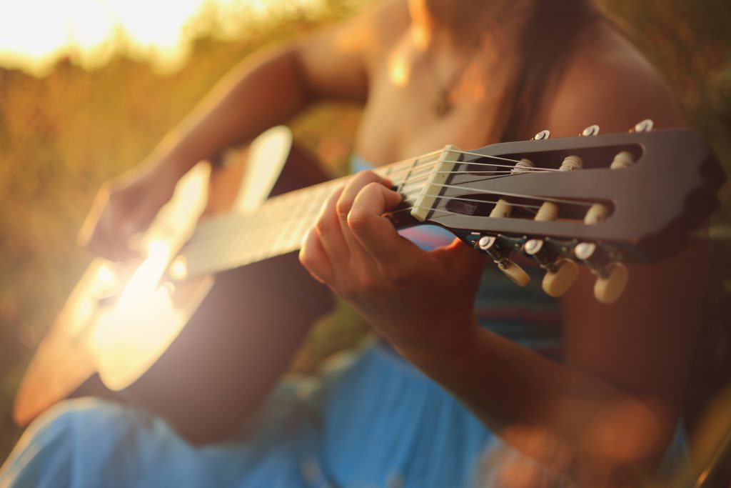 Beautiful woman playing the acoustic guitar in field